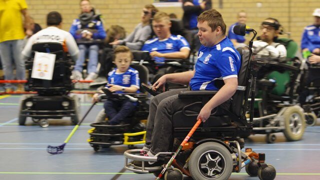 Nico op volle snelheid met hockeybal in stick. Stijn en Maik op achtergrond